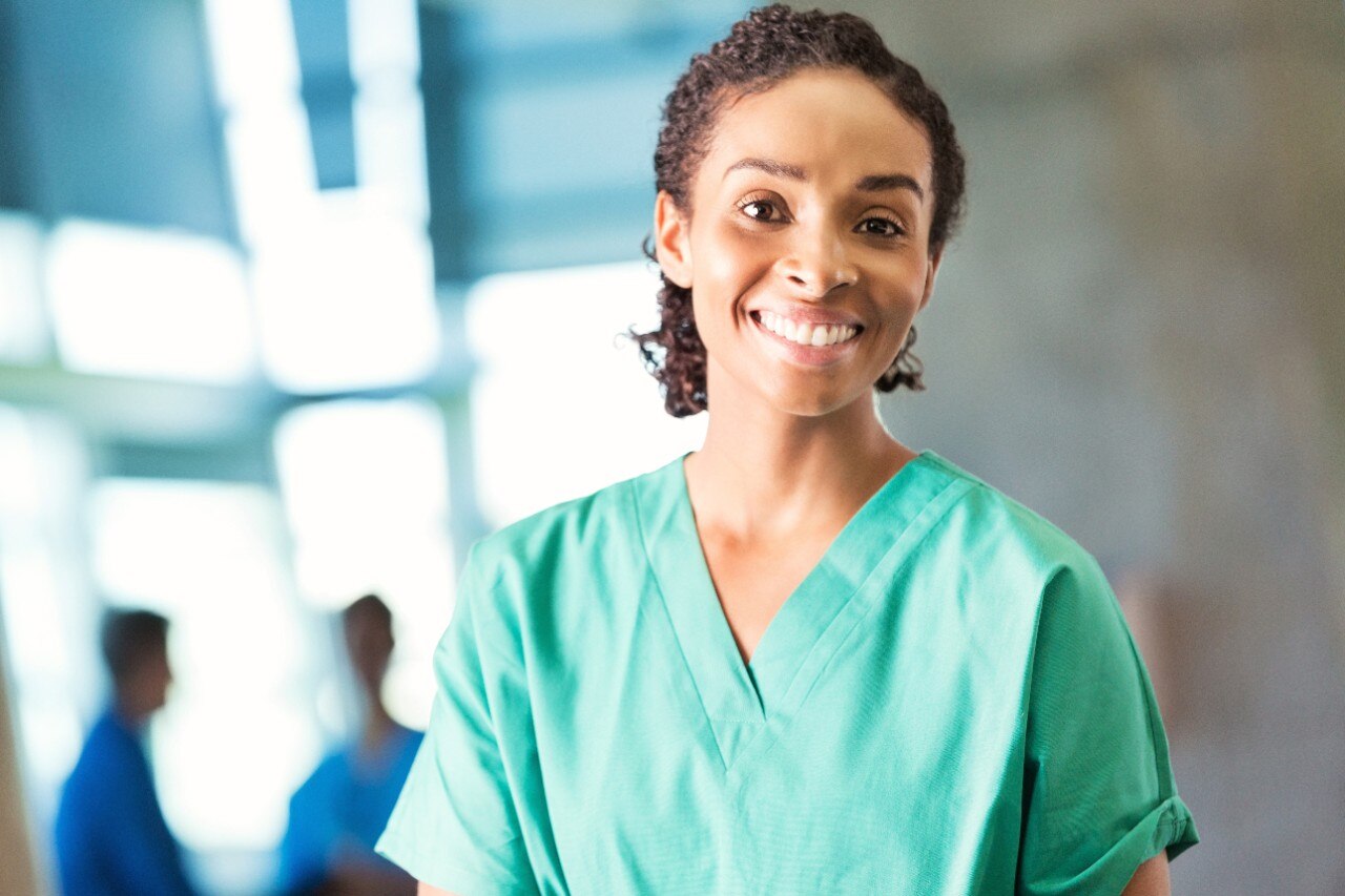 Female medical professional wearing green scrubs takes portrait