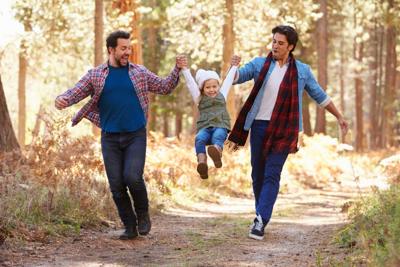 Two dads walking outside with daughter