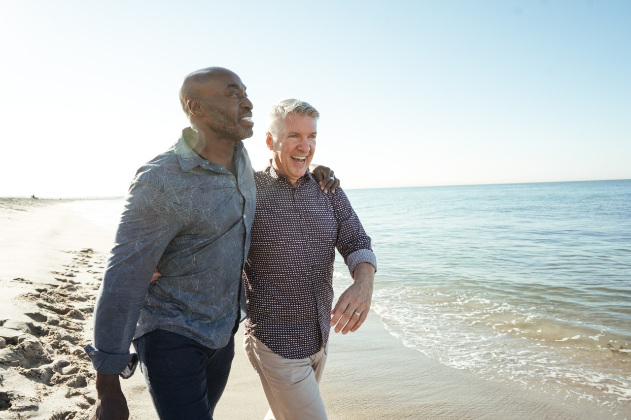 Two men having fun while walking on a beach