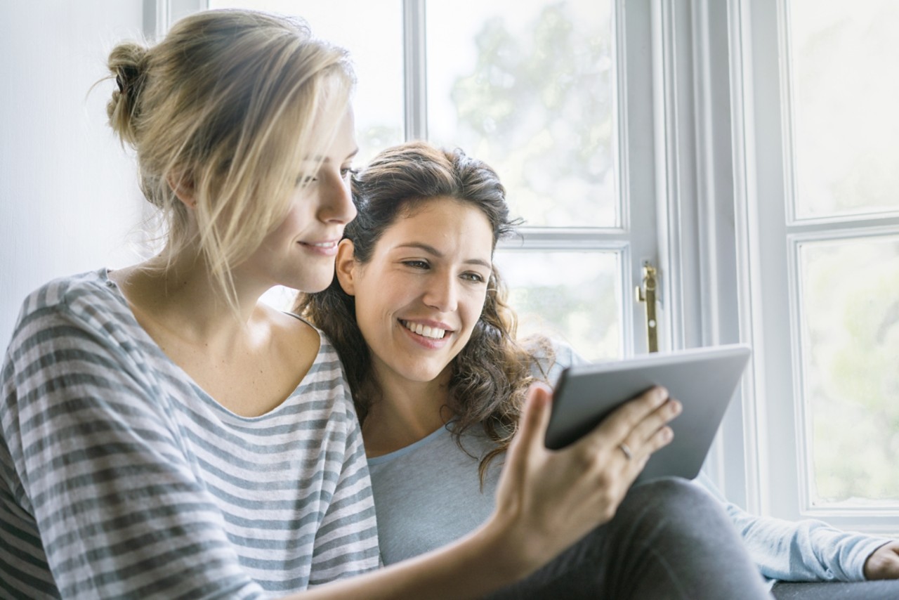 Women sitting together holding handheld device