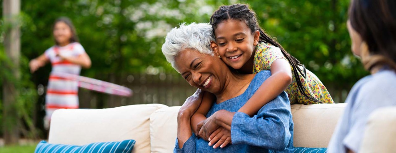 A photo of grandmother and daughter and grandchildren in a backyard.